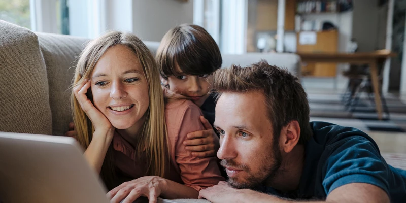 Familie kigger på en computer og læser, hvordan de ansøger om et privatlån hos Coop Bank