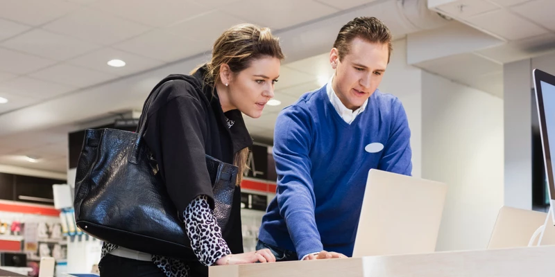 Kvinde og ung ekspedient der kigger på computer
