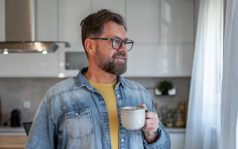 Mand med kaffekop i sit køkken