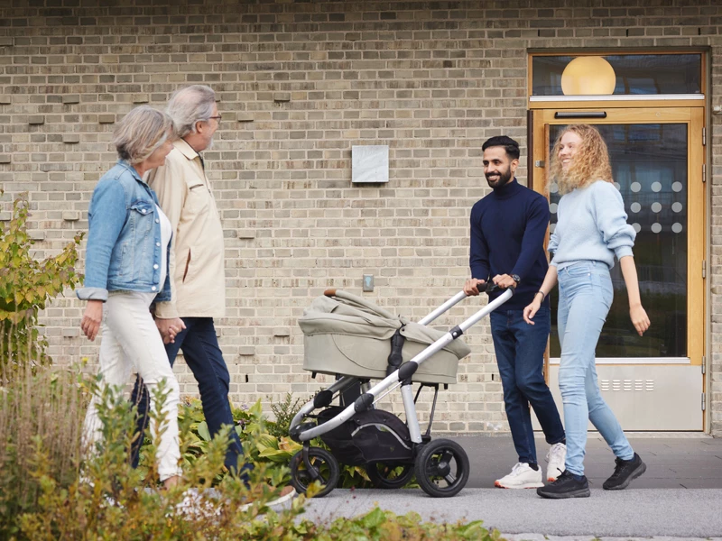 et par med barnevogn møder ældre par foran hus