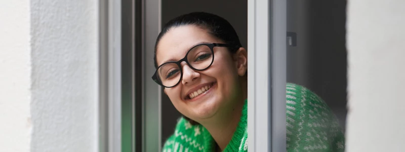 Kvinde kigger smilende ud af vindue