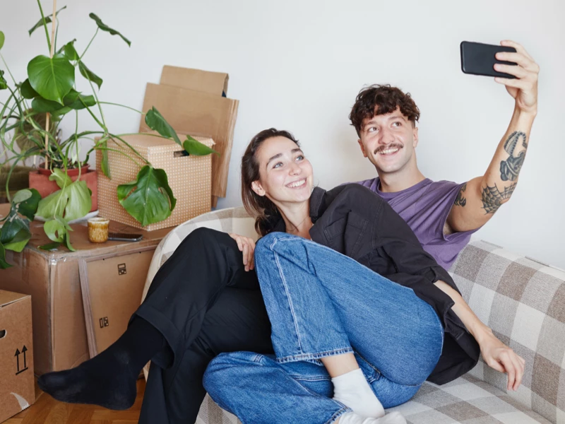 Ungt par sidder i sofa mens de tager et selfie