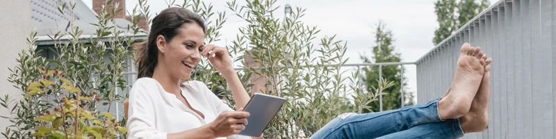 Kvinde sidder afslappet i sin have på sin tablet