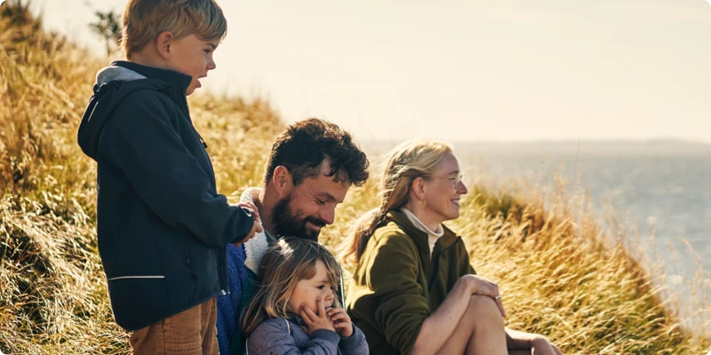 Familie på 4 sidder på skrænt tæt på havet