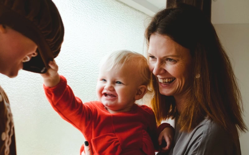 Glad kvinde med mørkt hår, der holder smilende baby