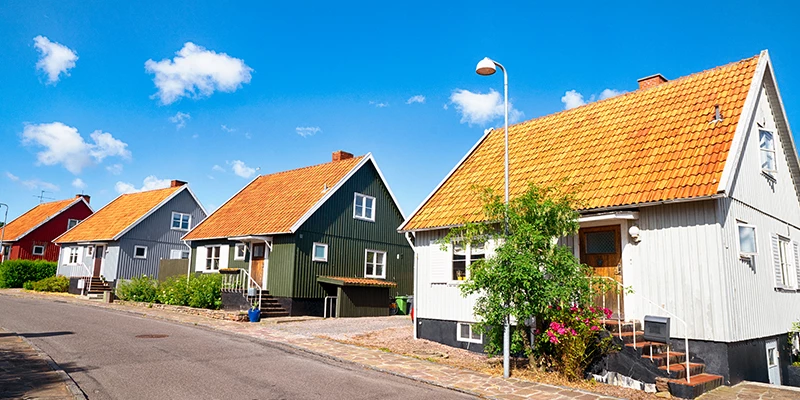 tre forskelligt farvede parcelhuse og blå himmel