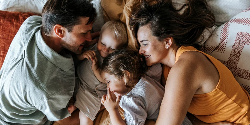 Mor, far, søn og datter ligger glade sammen i sengen