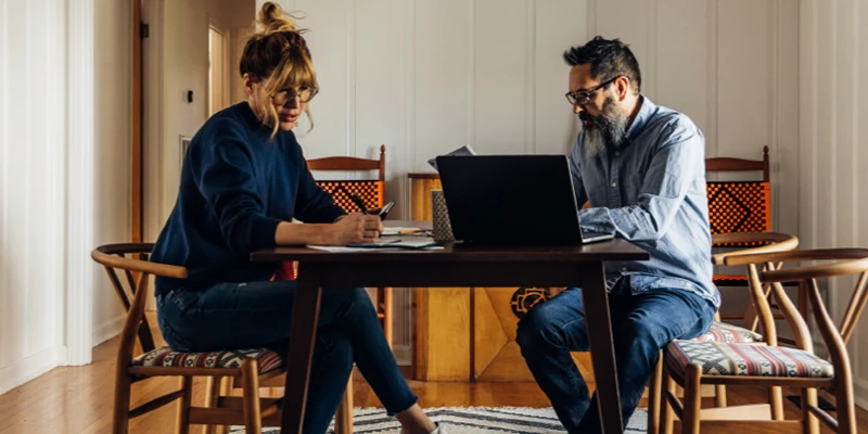 Kvinde og mand sidder i stue med computer og kigger på lån