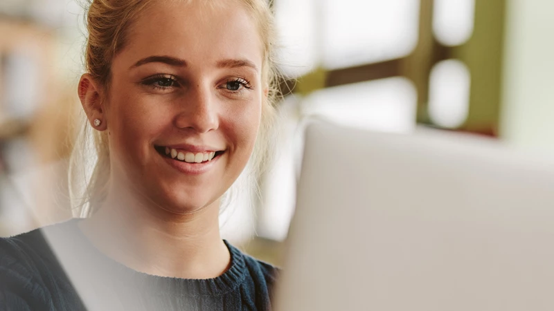 Glad ung kvindelig studerende foran sin computer