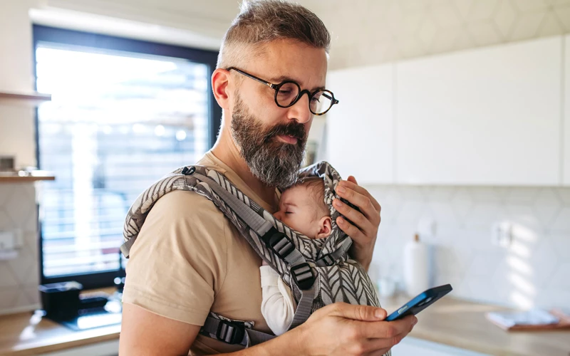 far i stuen med baby på maven og mobil i hånden