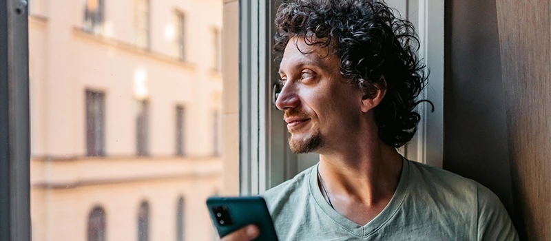 mand med krøller kigger ud af vindue