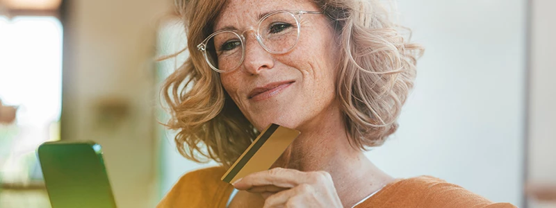 Kvinde med briller og krøllet hår kigger på mobil