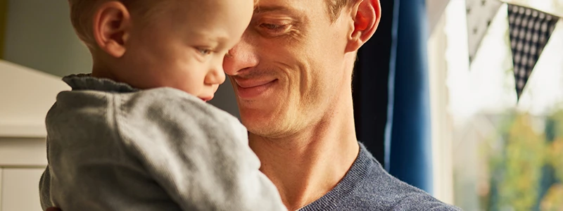 en smilende far med sit barn i armene