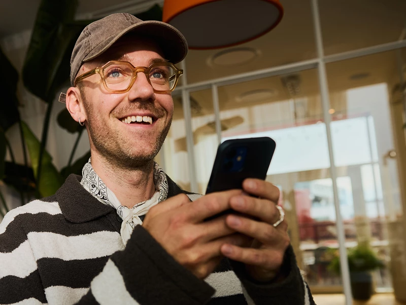 Mand med kasket og briller smiler over hans investering