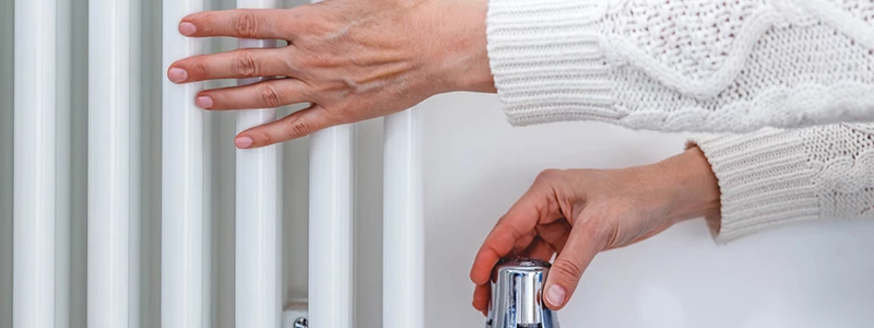 kvindehænder der skruer op for varmen på en radiator