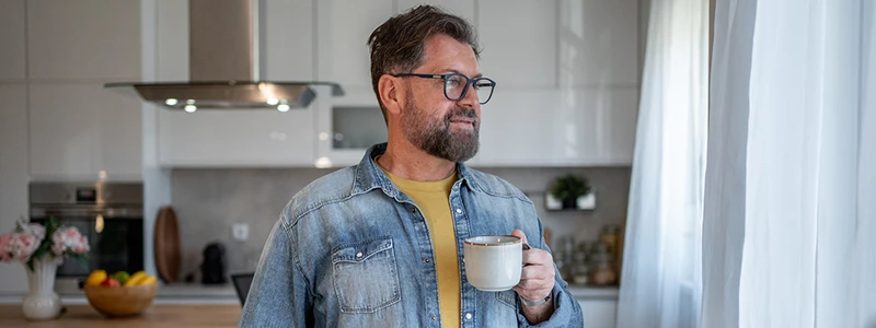 mand i 40'erne stående i køkken med kaffekop i hånden