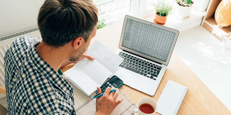 Mand med computer og lønseddel på bord i stue