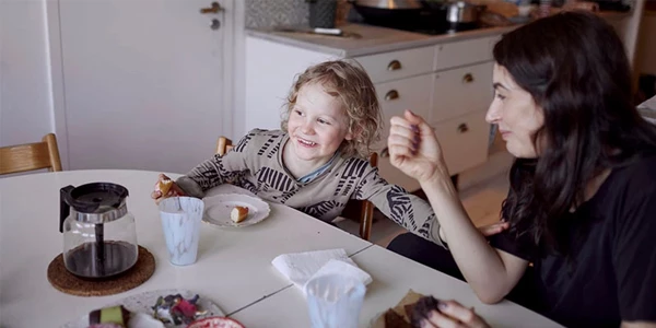 Mor og datter ved spisebord i stue