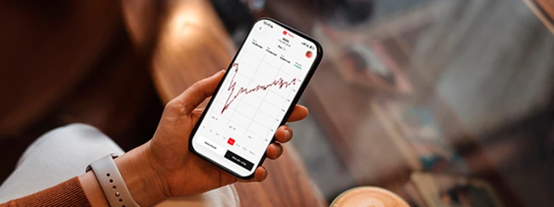 Kvinde med mobil i hånden med coop bank investering åben