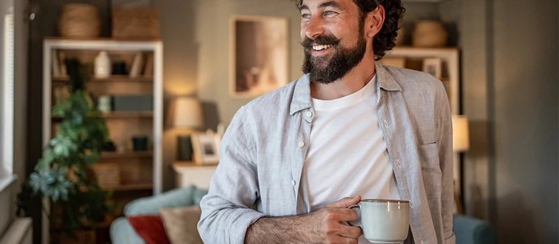 Tilfreds herre indenfor med grå kaffekop i hånden