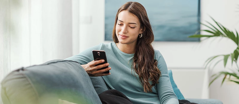 ung kvinde i stue mens hun kigger på sin mobil