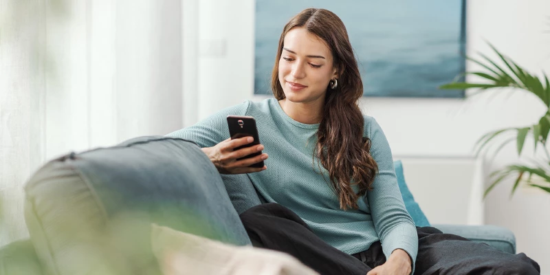 Kvinde i sin stue med en mobil i hånden