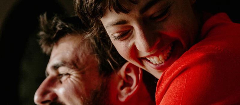 glad kvinde i rød trøje der krammer glad mand