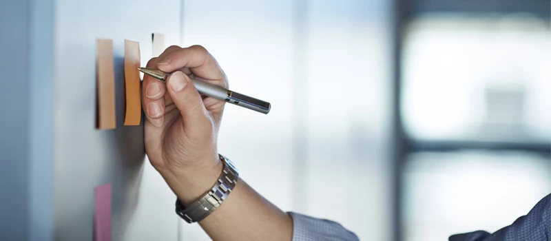 Arm med ur på der skriver på posters placeret på væggen