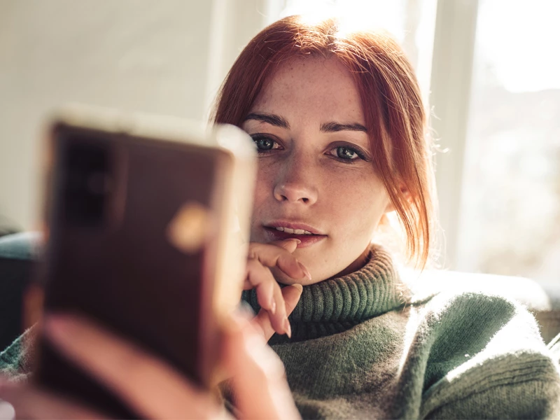 rødhåret kvinde kigger på sin mobiltelefon