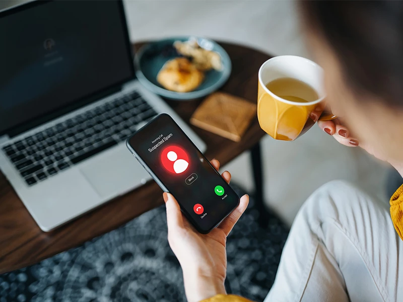 Siddende kvinde der spiser morgenmad foran computer og mobil