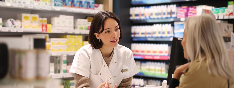 Ekspedient der rådgiver kunde på apotek
