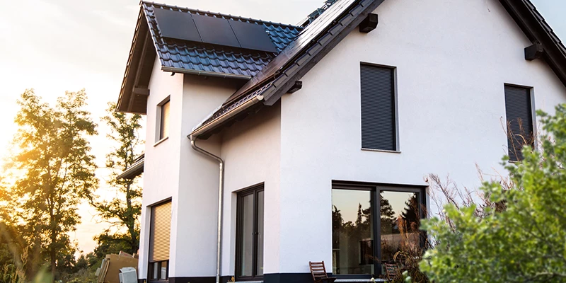 hvidt parcehus udenfor med skær fra sol i baggrund