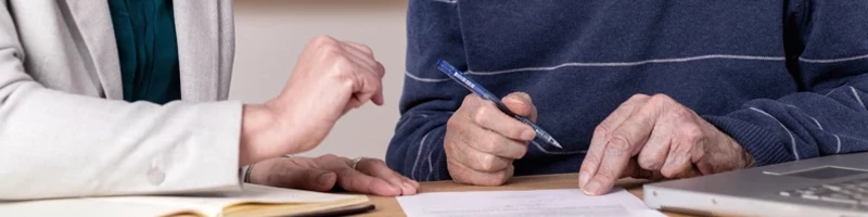 ældre der hænder på mand og dame der er ved at skrive under