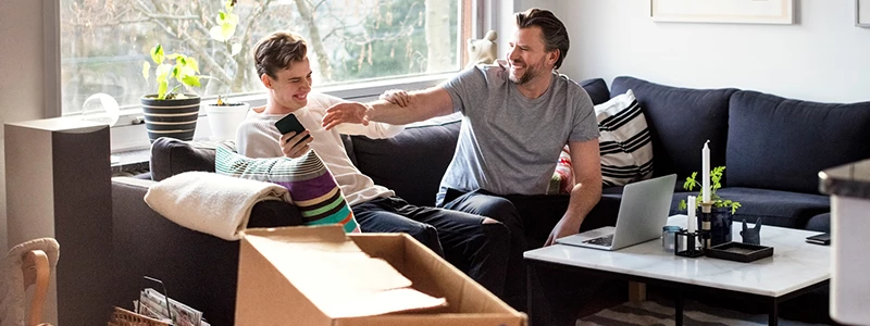 ung mand og hans far indenfor i stue i nyligt købt hus