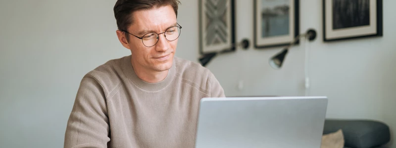 mand siddende bag sin computer i stue