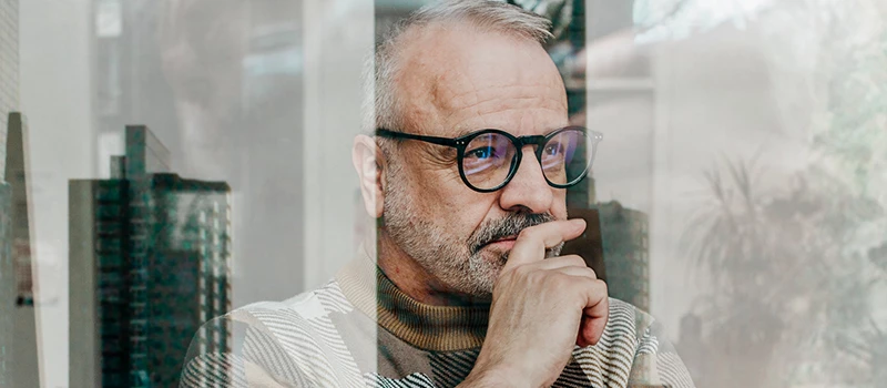 ældre mand kigger ud af vindue og tænker over tidshorisont