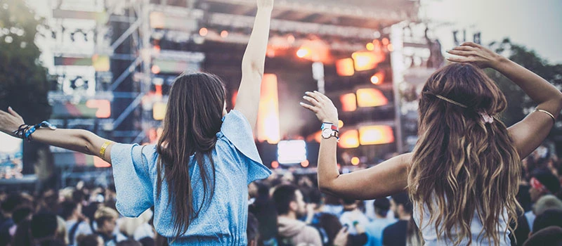 to piger i forgrunden til koncert på festival